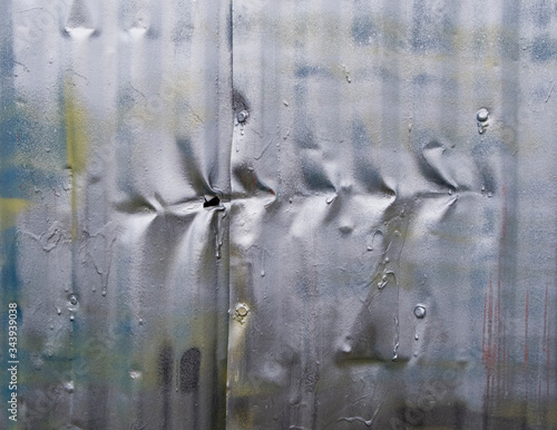 Row of indentation marks on silver spray painted metal wall, close up