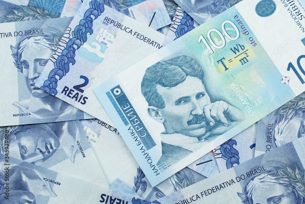 Fototapeta premium A close up of a blue and white, one hundred Serbian dinar bank note on a background of Brazilian two reais bank notes