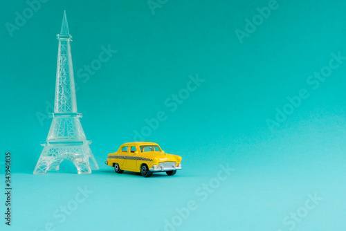 Yellow little retro car with Eiffel Tower on blue background.Travel concept. Planning summer vacations. 