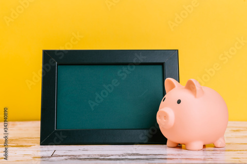 Pink piggy bank on wooden table and yellow background. The concept of storage, accumulation. Crisis, inflation, financial collapse.