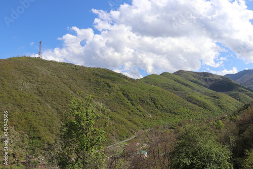 Armenia. There are many hills near the town of Kapan. In spring, all nature turned green. Without leaves yet nut trees. Over the hills spring clouds and blue sky.