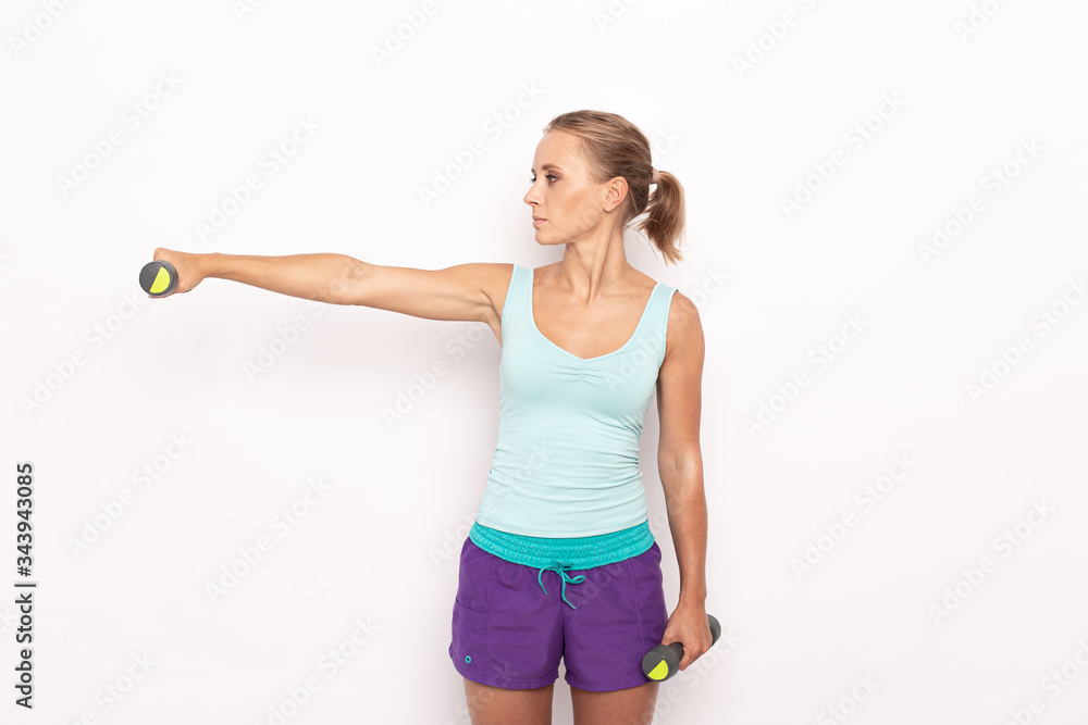 Blond sporty woman holds one hand with dumbbells in the air and the other lowered. White isolated background Blond sporty woman holds one hand with dumbbells in the air and the other lowered. White isolated background