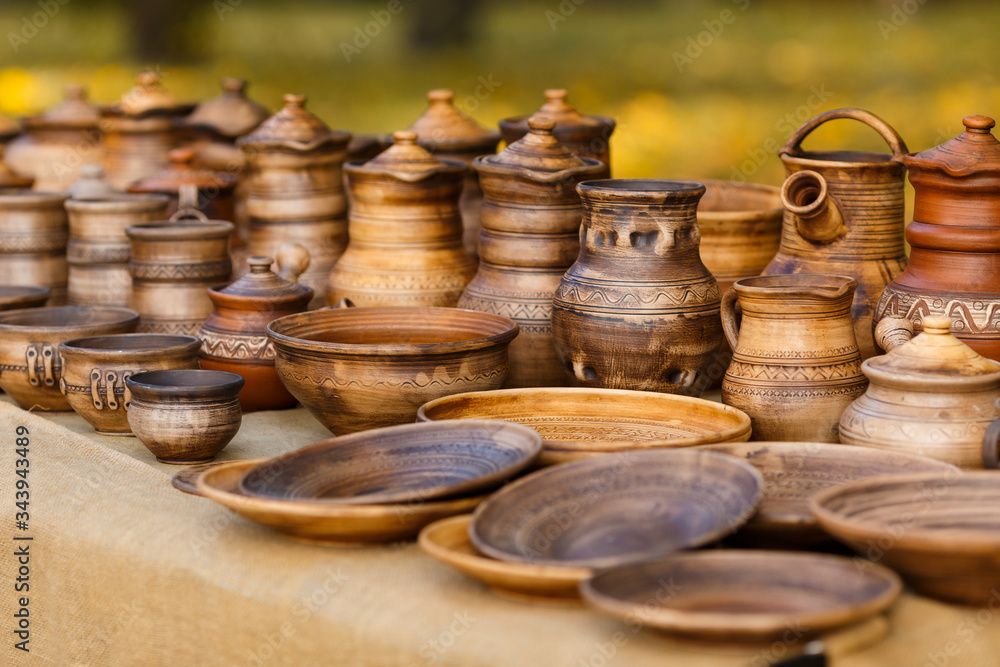 A lot of pottery - pots, jars, bowls, plates with ornaments are standing on the stall. Handmade dishes made of clay