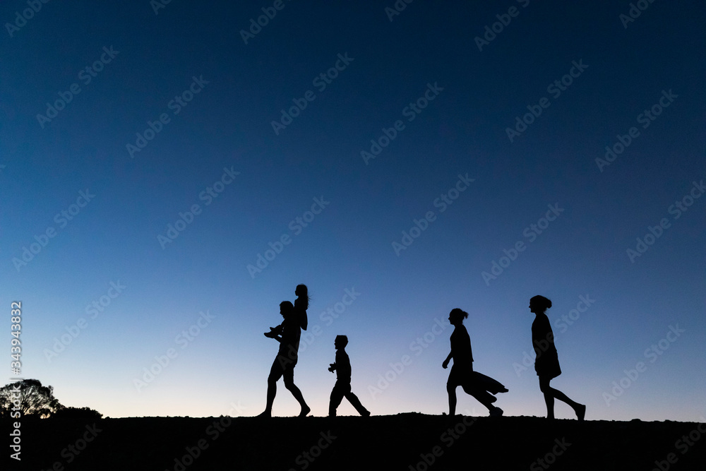 Silhouette family walking against blue sky at dusk Silhouette family walking against blue sky at dusk