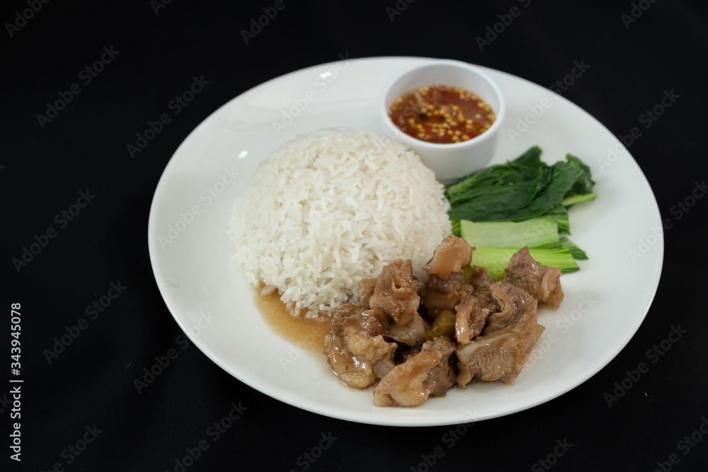 Stewed pork with rice, spicy sauce and vegetables. Black background 