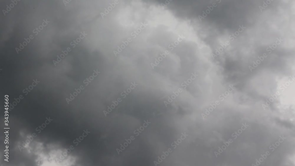 The sky is covered with gray clouds in anticipation of the rain. The clouds move fast. Between the gray clouds a gap is visible with white clouds lit by the sun The sky is covered with gray clouds in anticipation of the rain. The clouds move fast. Between the gray clouds a gap is visible with white clouds lit by the sun