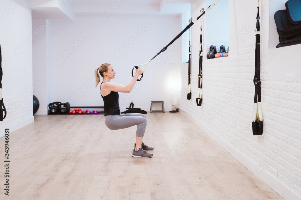 Fototapeta premium young woman practicing sport at the gym with trx. Healthy lifestyle