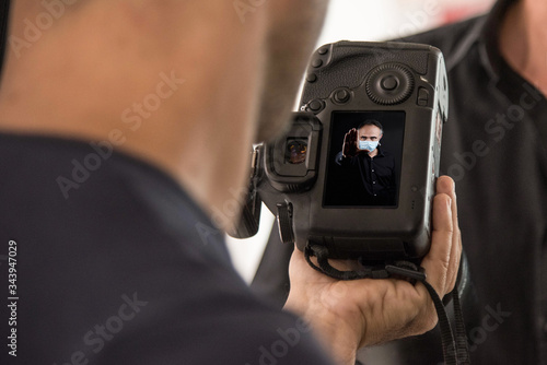 Macchina fotografica tenuta in mano che mostra lo schermino con sopra l'immagine di un uomo che indossa una mascherina chirurgica photo