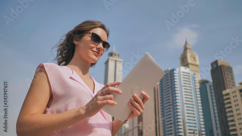 Photography A girl works on a tablet against the background of skyscrapers of a metropolis