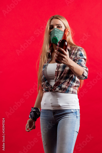 Emotional young blonde woman in a protective mask on her face with a Molotov cocktail in her hands protests photo