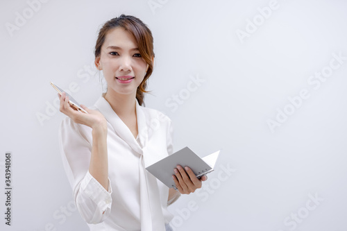 Portrait of a businesswoman holding a notebook and telephone in a white background