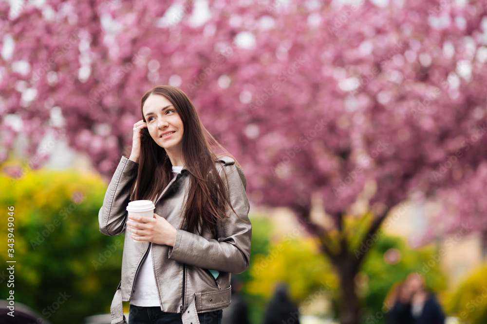 Women's beauty and fashion. Urban lifestyle. girl on the background of pink flowering trees. Closeup portrait of girl in spring Women's beauty and fashion. Urban lifestyle. girl on the background of pink flowering trees. Closeup portrait of girl in spring