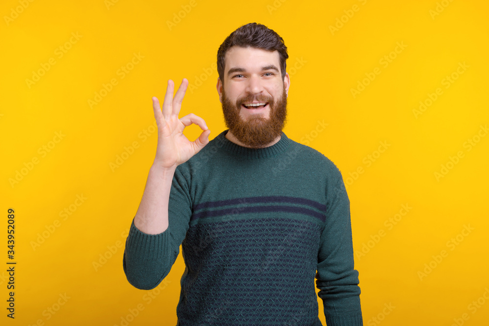 Portrait of a young bearded man showing ok gesture on yellow background. Portrait of a young bearded man showing ok gesture on yellow background.