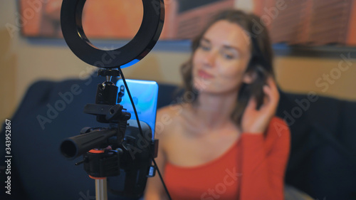 Fotografie A beautiful girl broadcasts live at home using a phone.