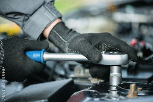 Car service worker is removing a front shock absorbers of a car close up.