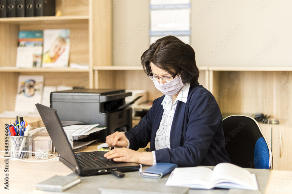 Woman in a mask on her face working in the office - coronavirus time
