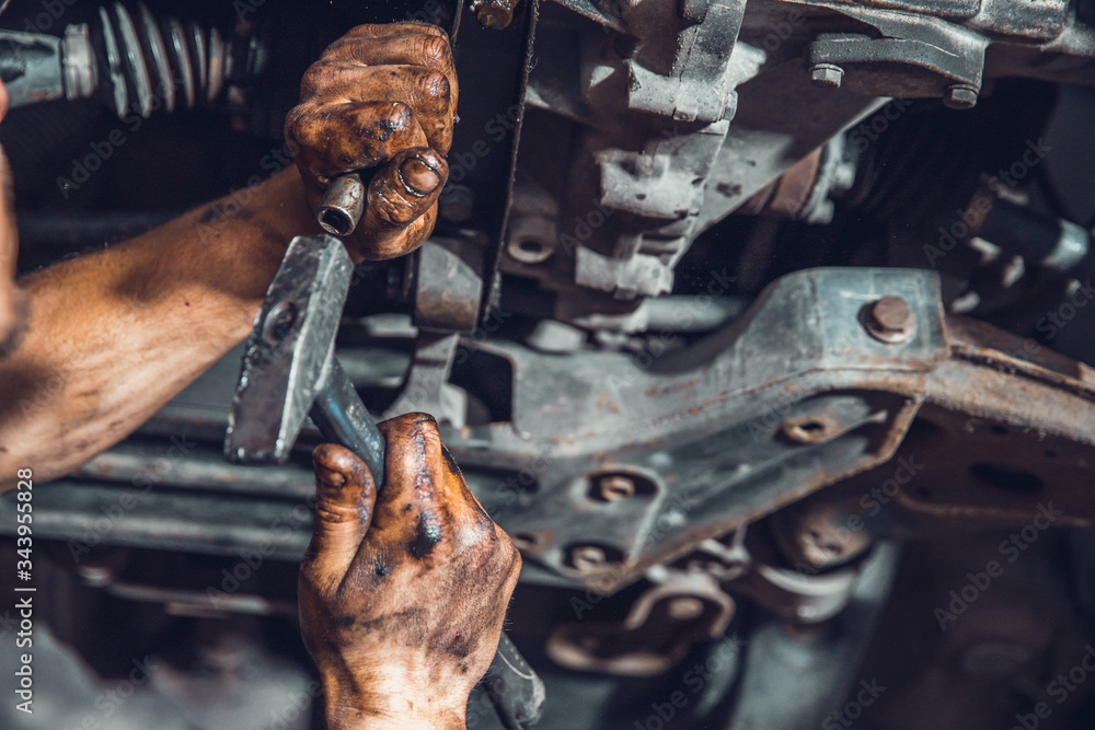 loosening the screw on the car during repair in the service with the help of the adjuster and hammer loosening the screw on the car during repair in the service with the help of the adjuster and hammer