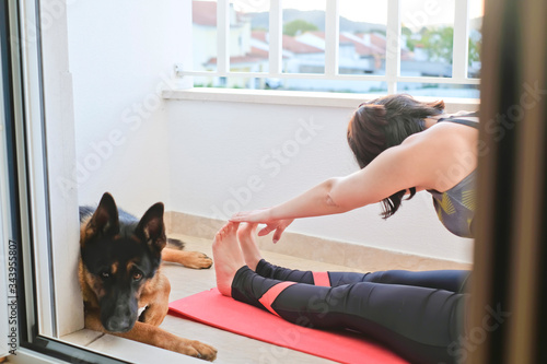 Health care - A woman stretching in her balcony during social distance with her german shepherd dog