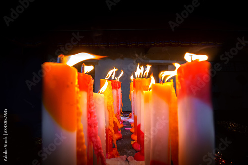 Numerous colorful candles are flaming in the temple. photo