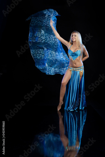 Young woman belly dancer in a blue oriental costume on a black background photo