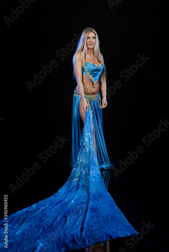 Young woman belly dancer in a blue oriental costume on a black background photo