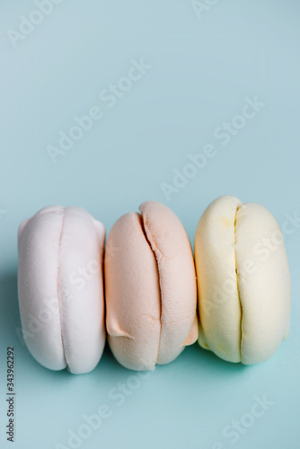 Delicious marshmallows in pastel colors on blue background. Clolrful zephyr. photo