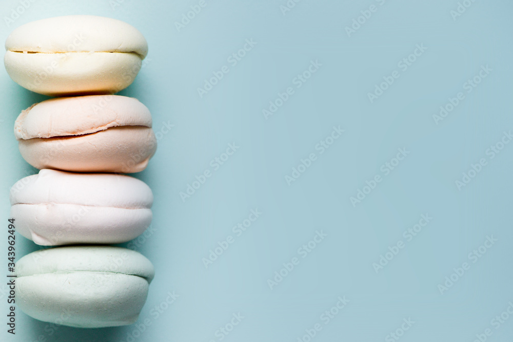 Gentle zephyr. close up. Air marshmallows in pastel shades on sky blue background. Gentle zephyr. close up. Air marshmallows in pastel shades on sky blue background.