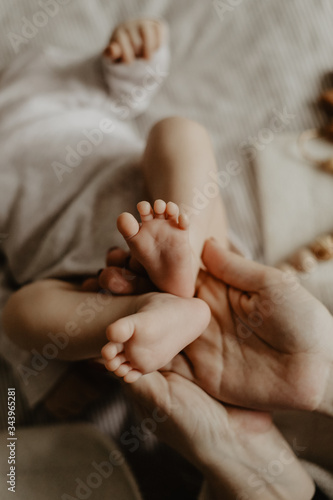 mother holds in her hands the legs of a newborn baby