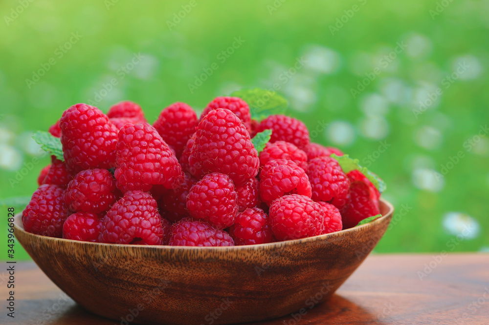 Ripe raspberries on bowl with nature background. Healthy eating concept Ripe raspberries on bowl with nature background. Healthy eating concept
