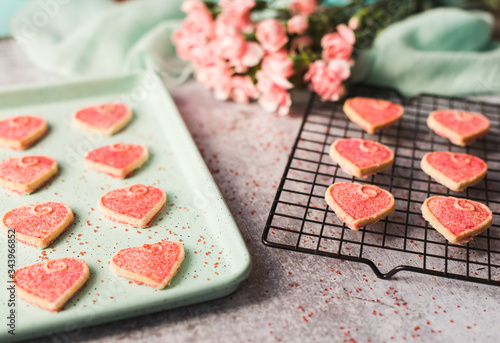 Close up of Valentine's day heart cookies cooling on a pan and rack. photo