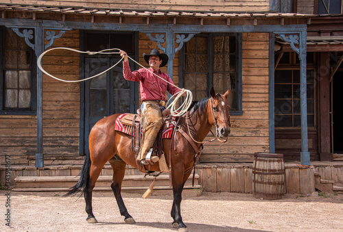 Cowboy using lasso while riding his horse through an old western town © Jim Babbage