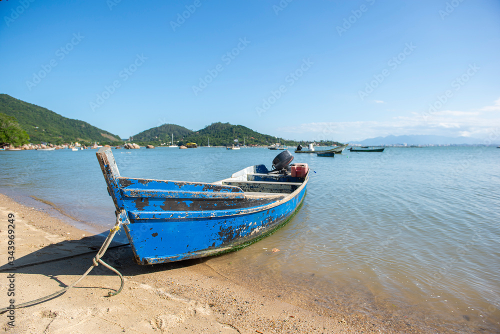 Fototapeta premium Front view of fishing boat on the beach with blue sky background in Florianopolis,