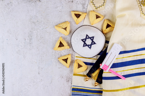 Jewish carnival Purim celebration on hamantaschen cookies, noisemaker and mask with parchment photo