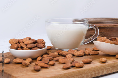 Almond milk in cup with nuts on white background