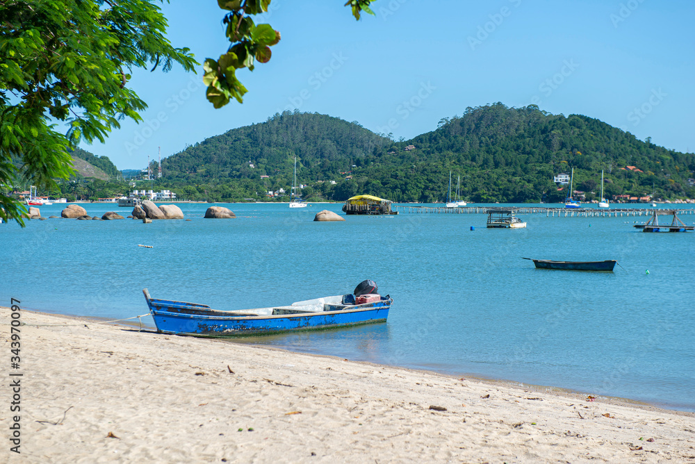 Beautiful beach landscape in Brazil. Calm turquoise sea with fishing boats and sailboats moored near the shore. Photo with space for text. Concept of tourism and beach holidays.