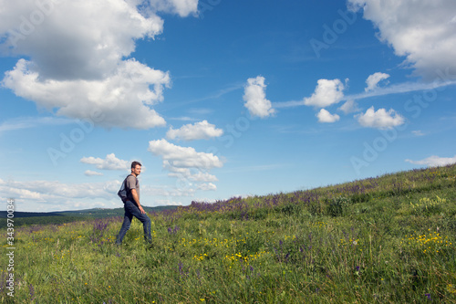 Adult man hiking on wooded hills in summer photo
