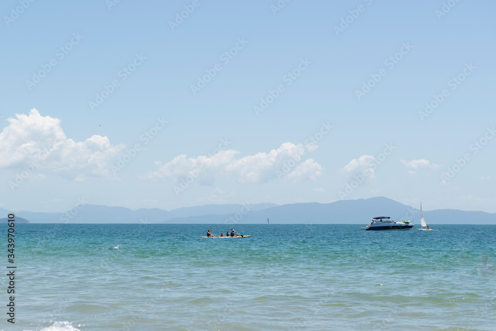 Speedboat on the horizon of the sea on a beautiful beach in the south of Brazil - City of Florianopolis. Beautiful view of greenish sea. Cloudless sunny day - clear sky in the summer. Speedboat on the horizon of the sea on a beautiful beach in the south of Brazil - City of Florianopolis. Beautiful view of greenish sea. Cloudless sunny day - clear sky in the summer.