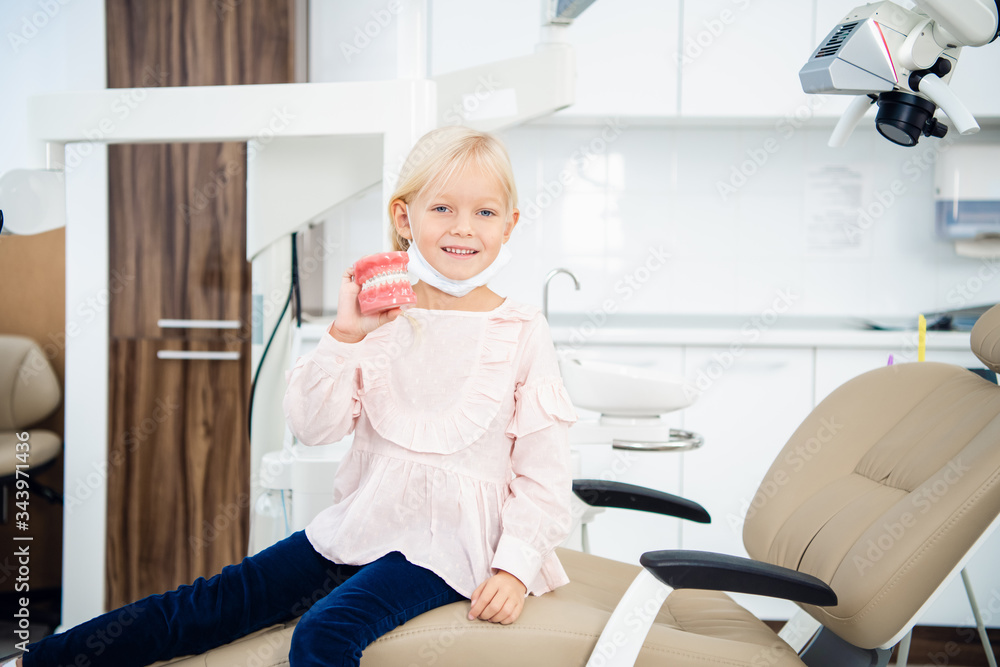 A girl in a dental office with artificial dentures in her hand A girl in a dental office with artificial dentures in her hand