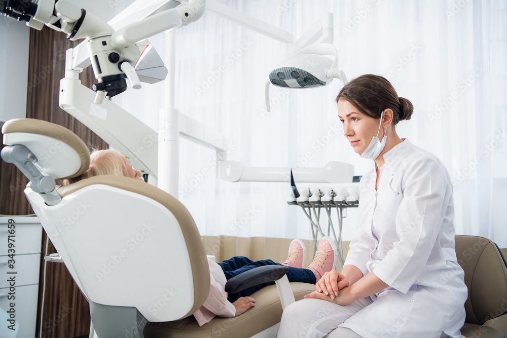 A female dentist talking to her patient trying to set up a contact with her to comfort her before the check up A female dentist talking to her patient trying to set up a contact with her to comfort her before the check up
