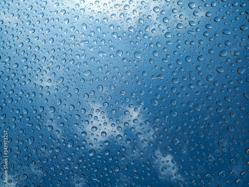 Drops of water on the glass. Sunny daytime blue sky. Transparent dew drops after rain. Bright photo with space for text.