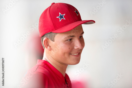 Close-up portrait of teen baseball player in red cap and uniform photo