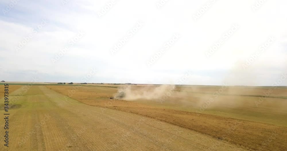 combine harvesting evolving in Canada Saskatchewan during sunset beautiful machinery wide shot from front with blue skies \flying thru dust and smoke cinematic 4K Aerial drone combine harvesting evolving in Canada Saskatchewan during sunset beautiful machinery wide shot from front with blue skies \flying thru dust and smoke cinematic 4K Aerial drone