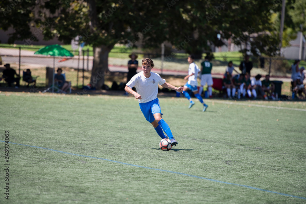 Teen soccer player dribbling the ball during a game Teen soccer player dribbling the ball during a game