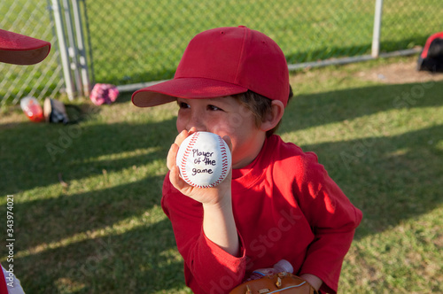 Young boy holding his player of the game baseball on the TBall field photo