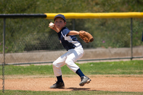 Little League baseball infielder ready to throw to first base