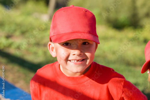 Young boy missing a tooth in red baseball cap smiling at camera photo