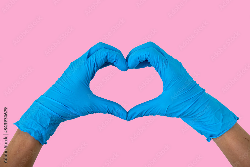 Obraz premium Human rising hands make finger heart shape wearing blue disposable latex glove, rubber glove for professional medical safety and hygiene protection from Coronavirus disease COVID-19 - Pink background