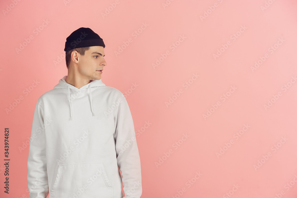 Looking at side. Caucasian young man's modern portrait isolated on pink studio background. Beautiful male model in white. Concept of human emotions, facial expression, sales, ad. Copyspace. Looking at side. Caucasian young man's modern portrait isolated on pink studio background. Beautiful male model in white. Concept of human emotions, facial expression, sales, ad. Copyspace.