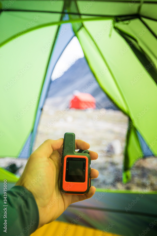 © Cavan Images - Man holds GPS and satellite safety communication device in tent. © Cavan Images - Man holds GPS and satellite safety communication device in tent.