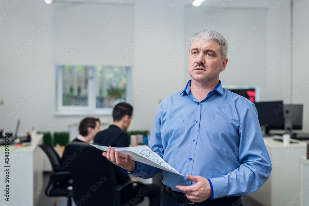 A portrait of the head of an architect bureau with his team in the back A portrait of the head of an architect bureau with his team in the back